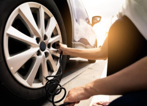checking tire pressure and pumping air into the tire of car wheel