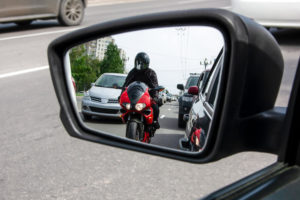 A red, sporty, motorcycle moves between the lane, dangerously close to cars.